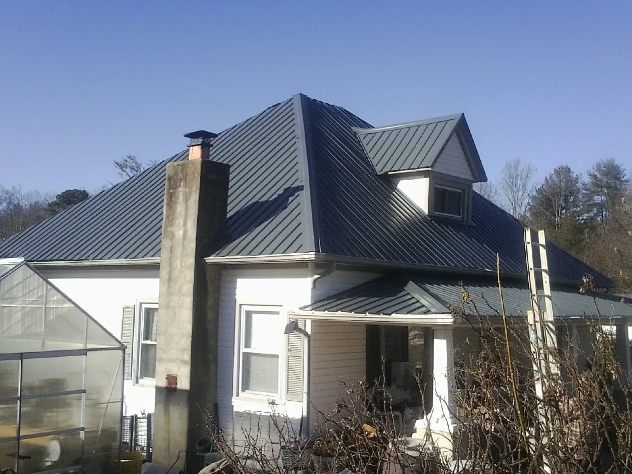 Dark blue standing seam metal roof on a white farmhouse with dormer — Slate & Tile Roof Repair by Roofing Brothers in Hamler
