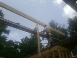 Carpenter setting a ridge beam over a new addition frame — Ice Dam Removal by Roofing Brothers in Hamler