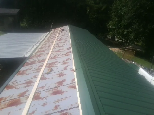 Old rusted panels beside newly installed green metal roofing — Wind Damage Roof Repair by Roofing Brothers in Hamler