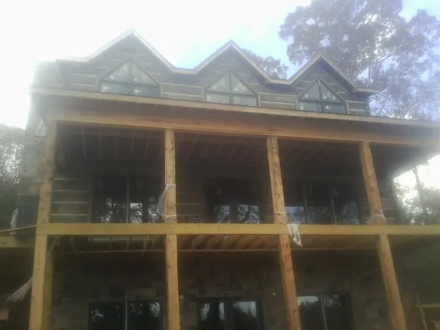 Dormers and porch framing on a large log home under construction — Roof Coating work by our crew in Hamler