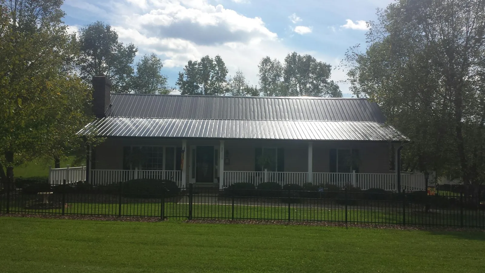 Gray metal roof on a brick ranch with a full width front porch — Gutter Guard Installation work by our crew in Hamler