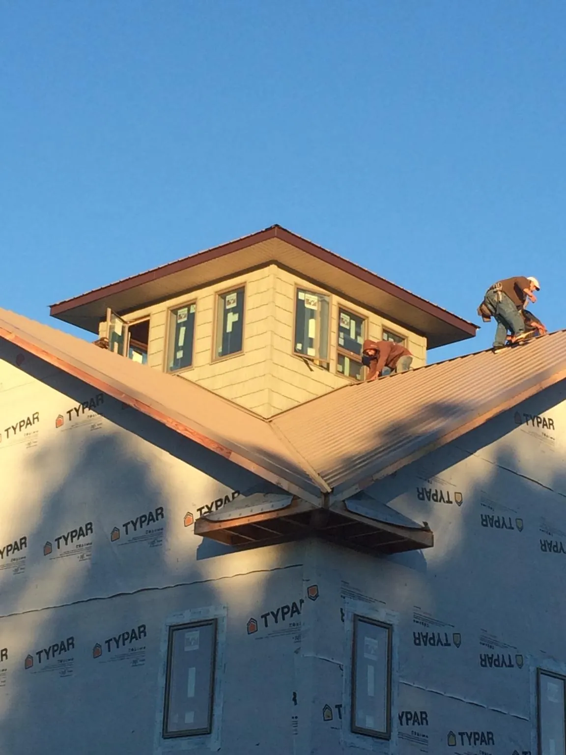 Roofers working around a rooftop cupola on a new metal roof at sunset — Roof Waterproofing in Hamler by Roofing Brothers